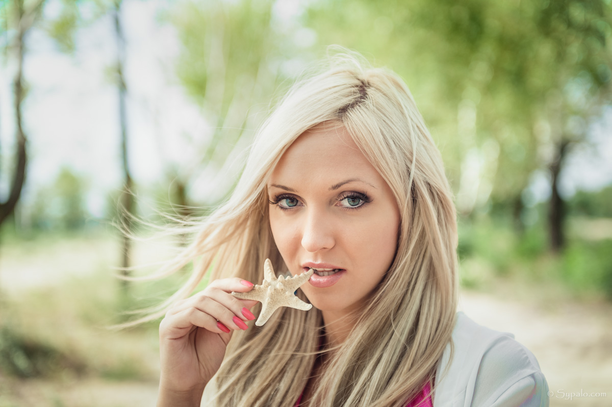 A portrait of a blonde biting a starfish toy