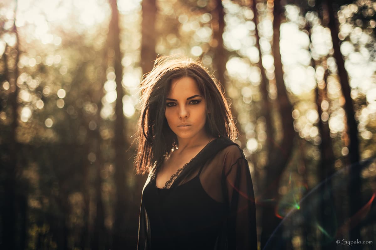 A witch in a black dress standing in a forest