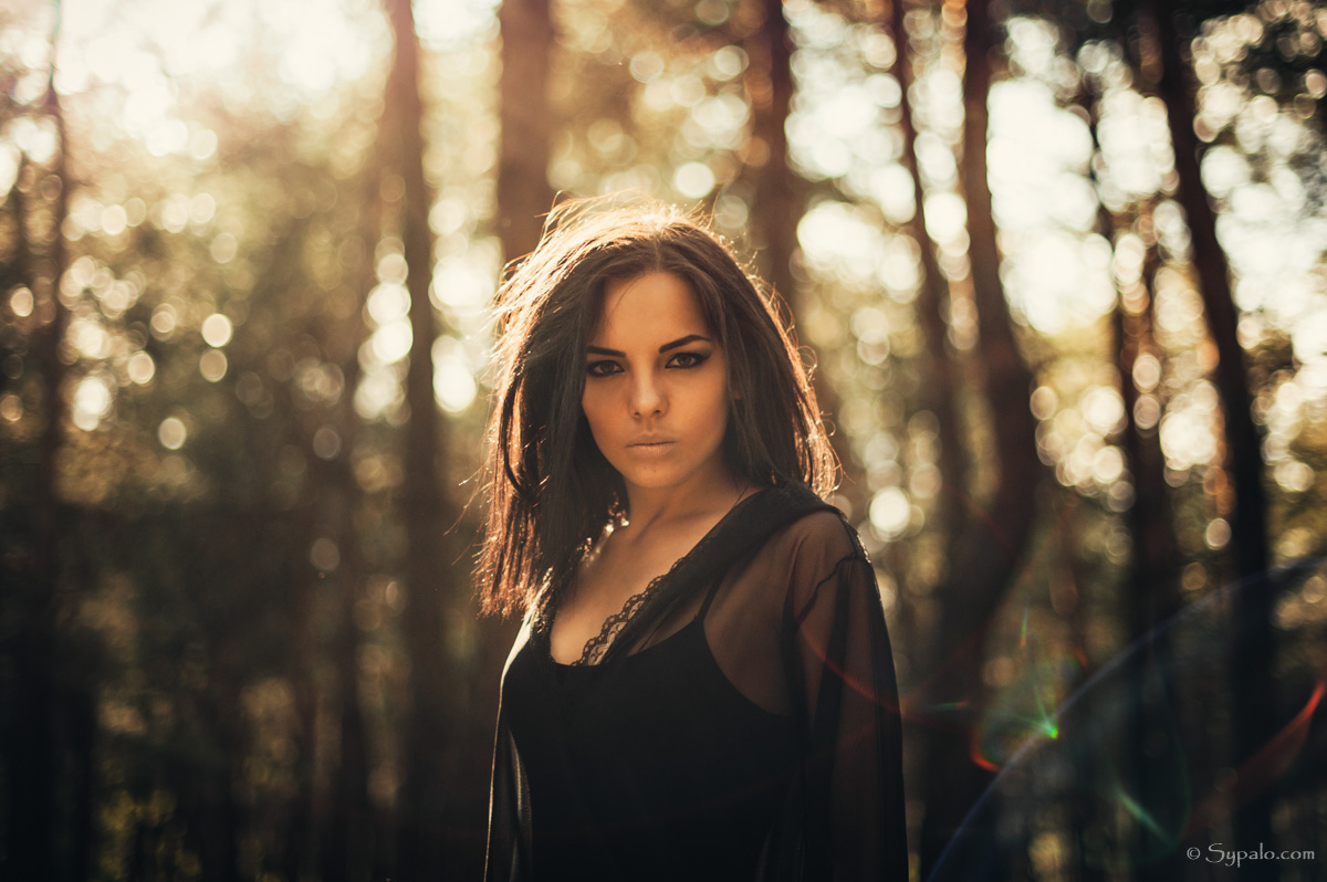 A witch in a black dress standing in a forest